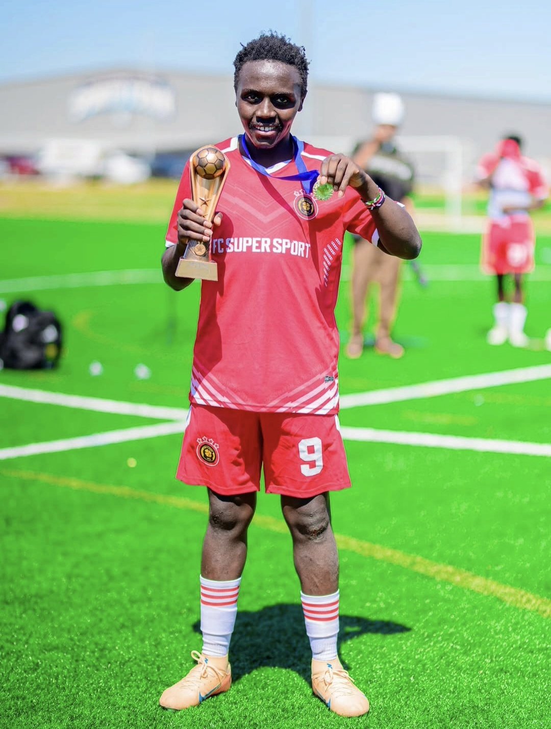FC Super Sport player number 9 holding the trophy and showing his medal