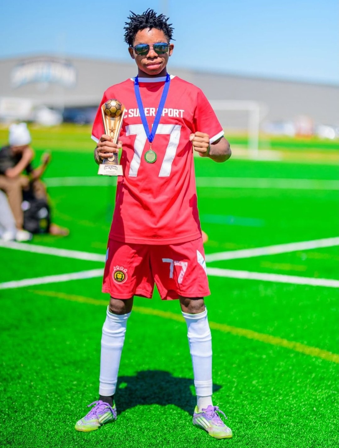 FC Super Sport player number 77 holding the trophy with his medal
