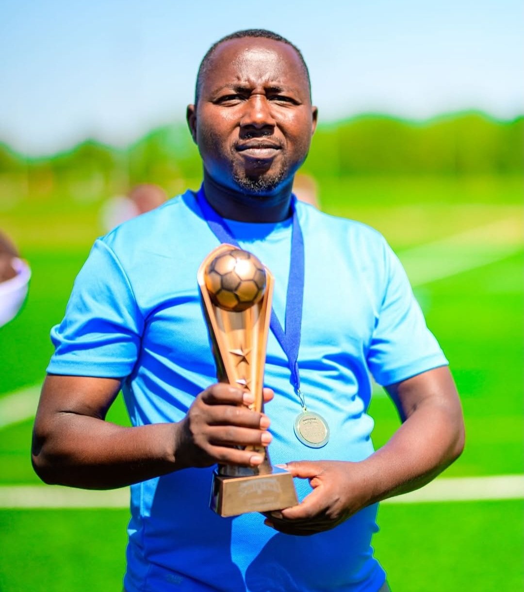 FC Super Sport coach in blue holding the championship trophy with his medal