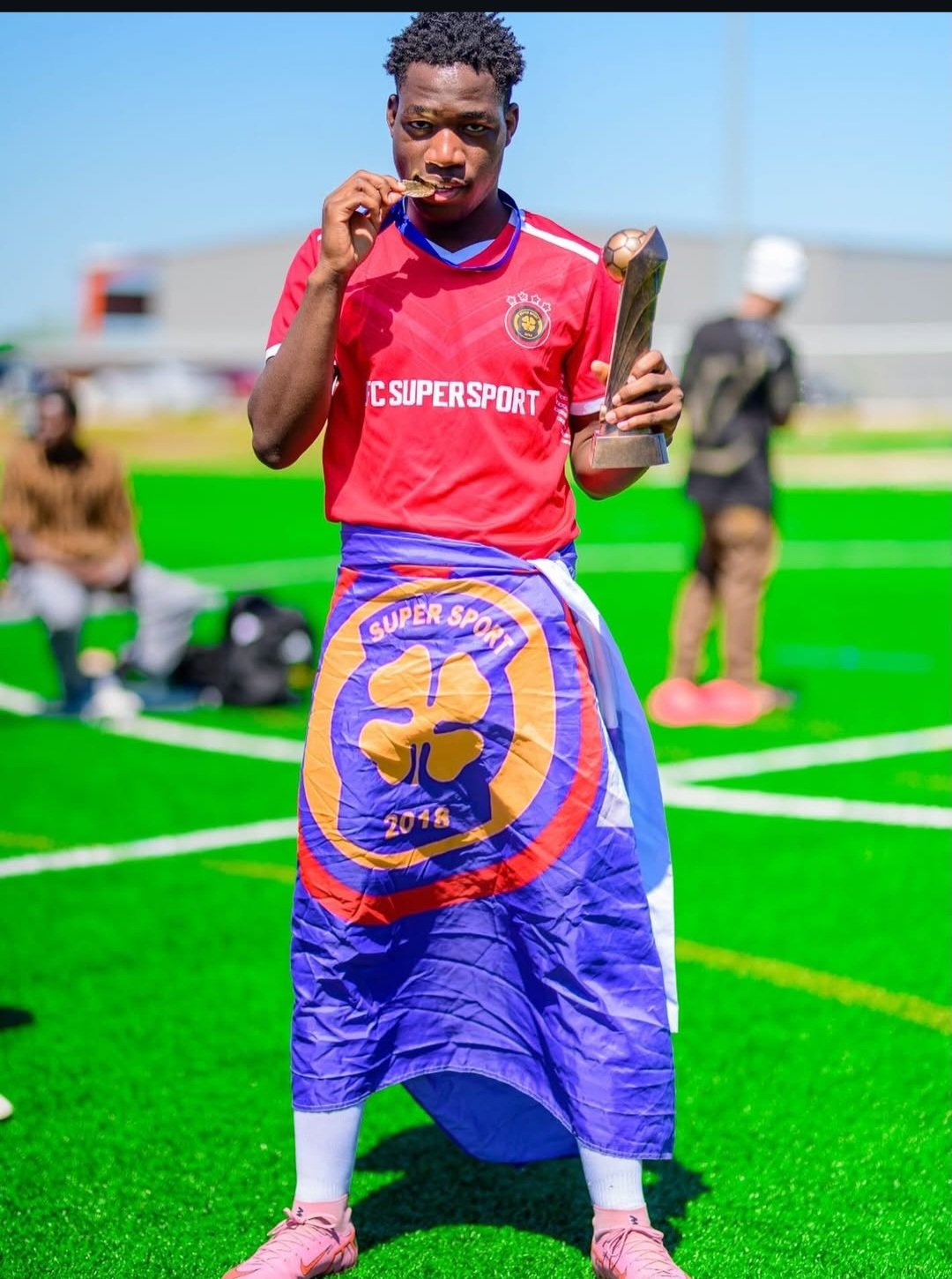 FC Super Sport player wrapped in the team flag holding the trophy