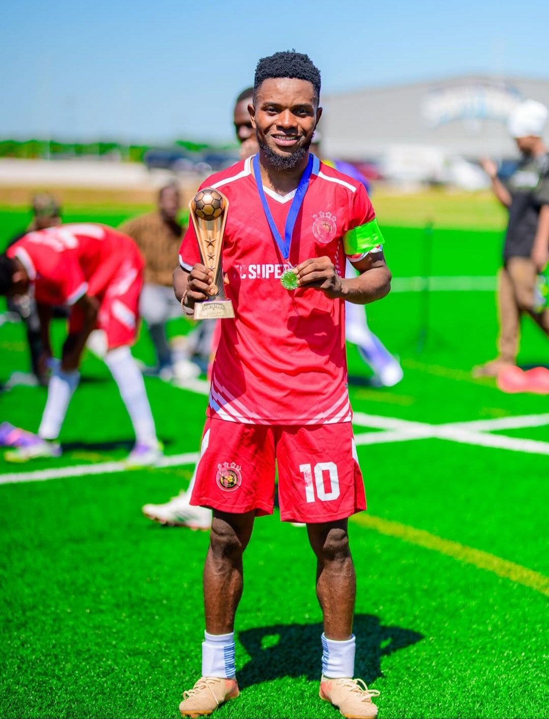 FC Super Sport player number 10 with the captain's armband holding the trophy and his medal