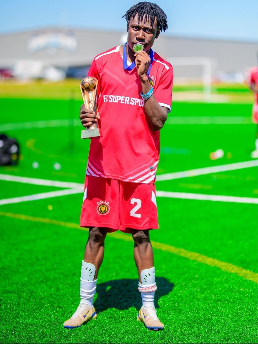 FC Super Sport player number 2 holding the trophy and biting his winner's medal