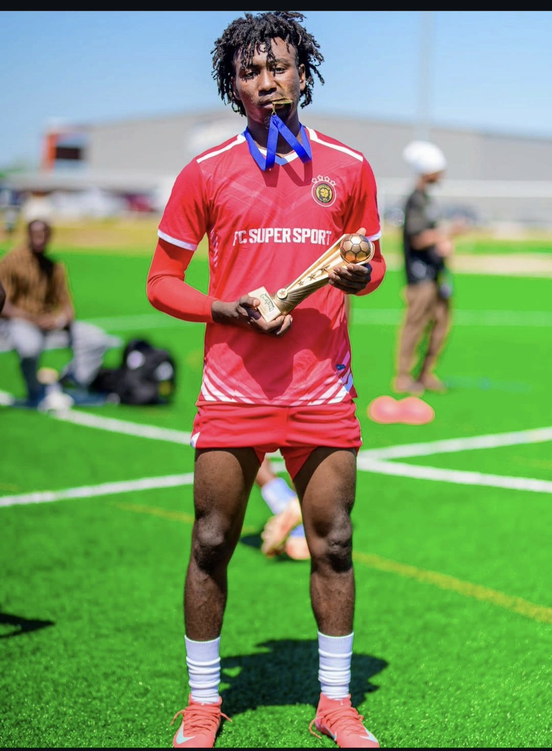 FC Super Sport player celebrating with the trophy and biting his winner's medal